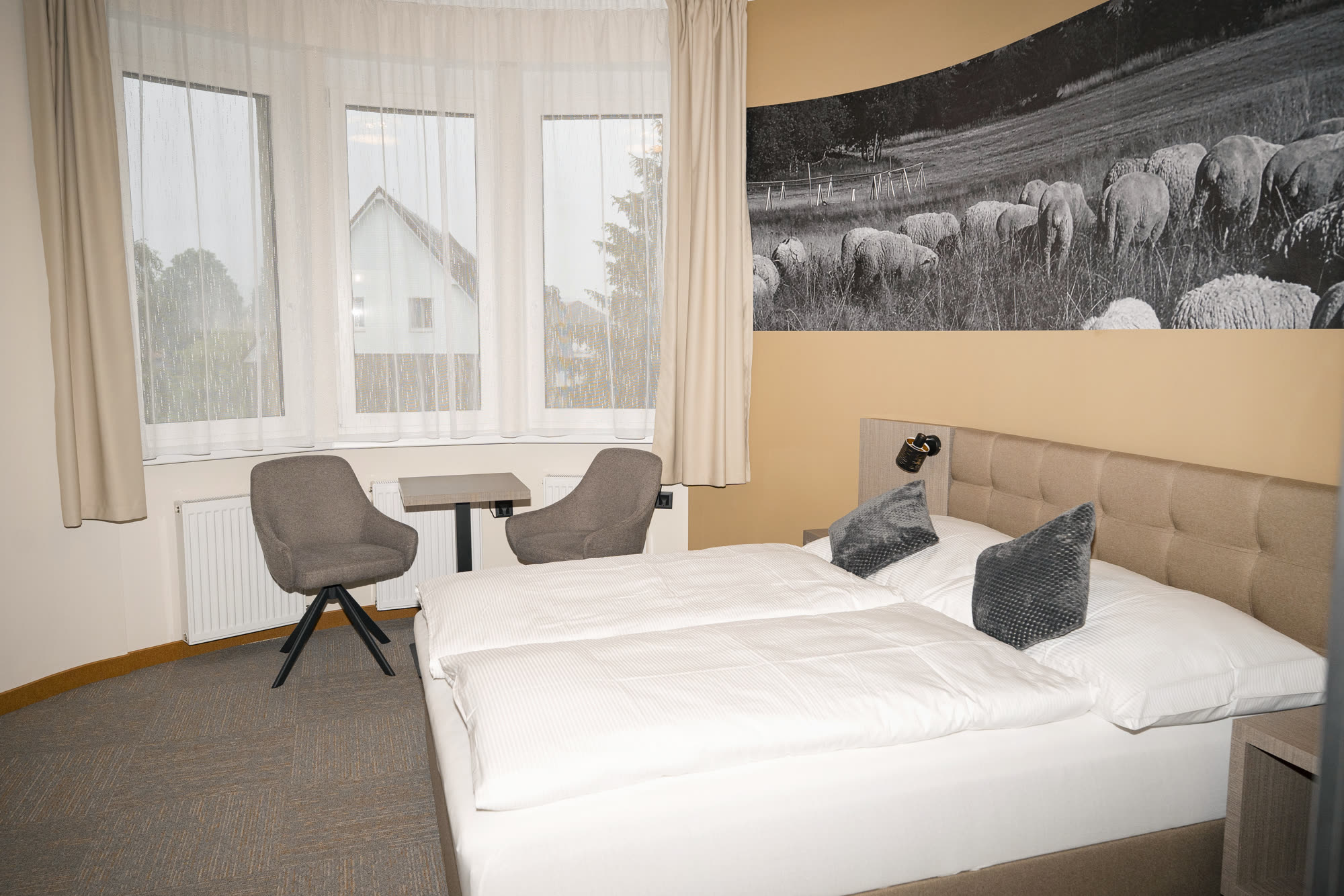 Dvojlůžkový pokoj s velkoformátovou fotografií ovcí